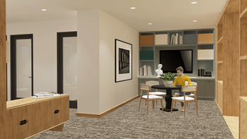 A person is sitting at a table in a room with a television and a bookshelf at Portrait Midtown Apartments, Carmel, 46032